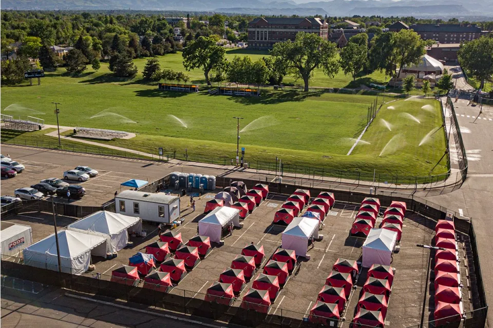 Ice fishing tents surrounded by fence in Safe Outdoor Space for unhoused people in parking lot in Denver, Colorado.
